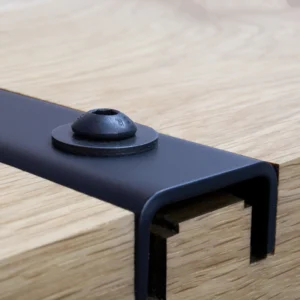 Nahaufnahme des präzise gefrästen Langlochs einer schwarzen Gratleiste zur flexiblen Verschraubung an der Tischunterseite.