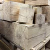 Holzklotz Eiche massiv für DIY Projekte als sägeraue und unbehandelte Rohlinge auf einer Palette in der Schreinerei.