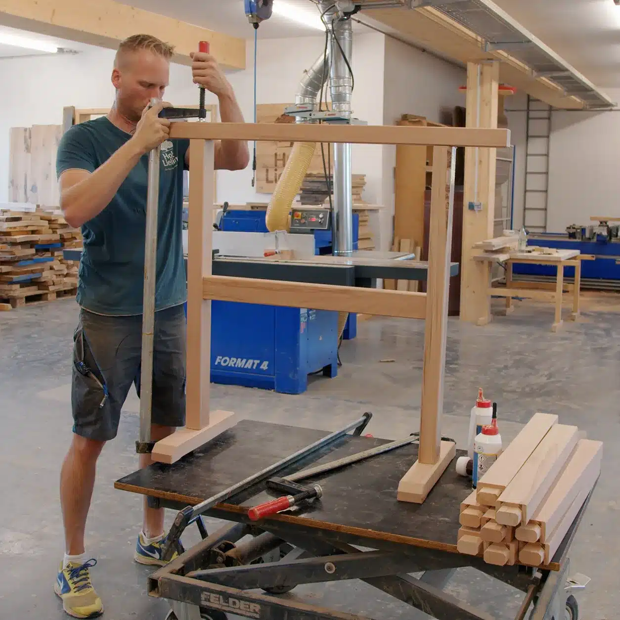 Fixieren des zusammengebauten Buchen-Arbeitsbocks mit einer Schraubzwinge beim Verleimen