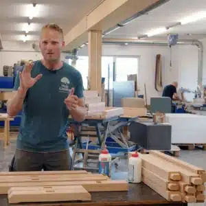 Marco praesentiert die 6 vorgefraesten Einzelteile des Arbeitsbock Bausatzes aus massiver Buche in der Schreinerei