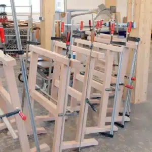 Reihe frisch verleimter Arbeitsboecke aus Buchenholz mit Schraubzwingen in der Schreinerei